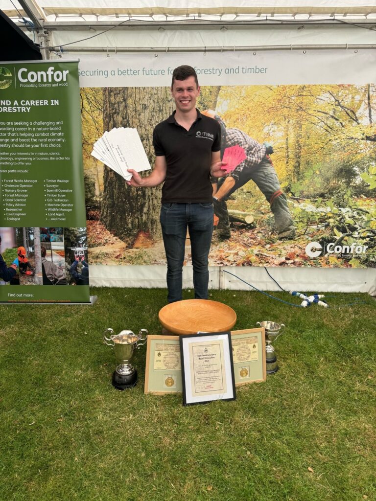 Arwel stands holding the awards he has won with trophies around his feet.